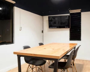 A meeting room with a screen mounted in the corner of the wall displaying Q-Play.
